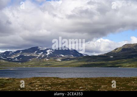 Montagne innevate e un lago durante l'estate su un altopiano in Norvegia, vicino a Hemsedal Foto Stock