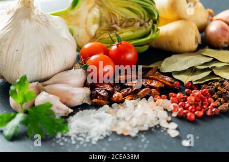 Mazzo di verdure mature assortite e spezie secche su cui giace sfondo grigio Foto Stock