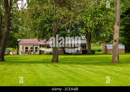 Chesapeake City, MD, USA 08/25/2020: Una vista panoramica grandangolare di una vecchia casa suburbana a un piano unico nel bosco con un grande cortile. Un panno lungo li Foto Stock