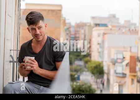 Uomo rilassante con caffè sul balcone Foto Stock