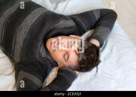 Sorridente bell'uomo sdraiato sul letto Foto Stock