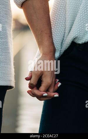 Crop mani di coppia in abbigliamento casual e manicure bianco Foto Stock