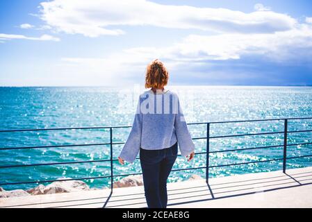 Donna in piedi al corrimano e guardando l'oceano Foto Stock