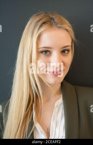 Bella giovane bionda Donna in scuro elegante vestito in piedi con fiducia con braccia incrociate e guardando la macchina fotografica sorridente su sfondo nero Foto Stock