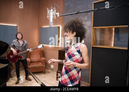 Bella Donna sorridente e scattante dita in musica durante le prove band in studio. Foto Stock