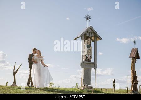 Giovane coppia newlywed in piedi al monumento e abbracciando Foto Stock