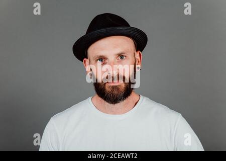 Barbuto tanga glabre in t-shirt e hat su sfondo nero Foto Stock