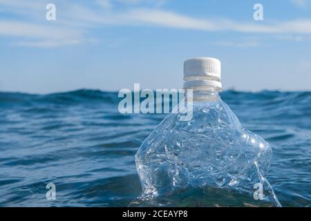 Una bottiglia di plastica galleggia sulla superficie dell'acqua in mare aperto. Concetto di ecologia Foto Stock