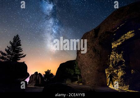 Silhouette di un uomo di notte esplorando una grotta in montagna con una torcia sotto un incredibile modo lattiginoso. Soria, Spagna Foto Stock