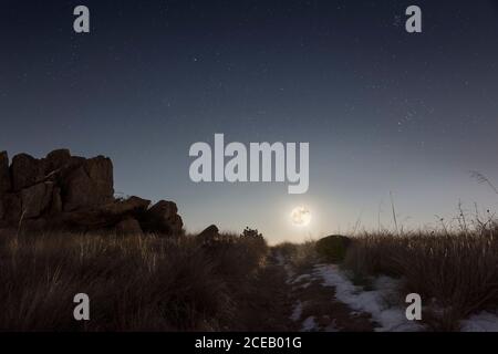 Luna piena che si erge sulla collina in una notte invernale Foto Stock