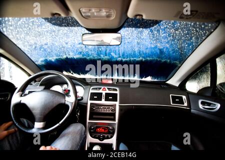 Ripresa dall'interno del conducente seduto sul sedile e sul parabrezza coperto di neve Foto Stock