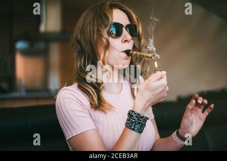 Donna che fuma marijuana in un bicchiere smussato Foto Stock