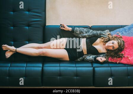 Donna sdraiata sul divano con vetro di cannabis smussato Foto Stock