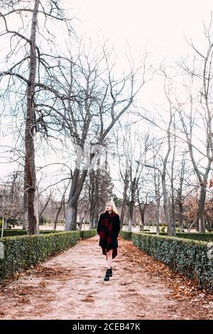 Giovane donna in vestito rosso a piedi nel parco Foto Stock