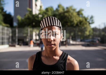 il ragazzo afro con cappello gioca a basket sul campo del suo quartiere Foto Stock