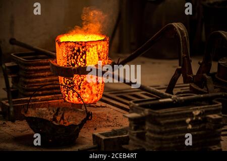 Vista del raccolto di maschio in abiti da lavoro in piedi e prevenendo calici in forno con fuoco acceso Foto Stock