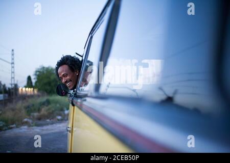 bella afro uomo gode il viaggio nel suo van vintage con alcuni amici Foto Stock