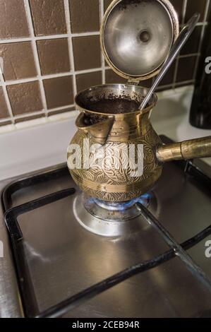 preparazione di caffè fresco in bronzo turco cezva su stufa a gas al mattino Foto Stock