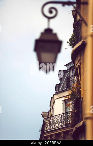 Vista ravvicinata della facciata dell'edificio con lanterna sfocata appesa Su muro a Parigi sullo sfondo di blu cielo senza nuvole Foto Stock