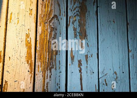 Primo piano di tavole di legno usurate con ombre blu contrastanti e la luce arancione Foto Stock