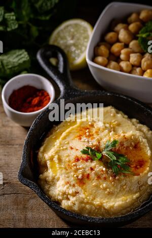 Humus di ceci fatto a casa. Con paprika, cetriolo e carota. Su vecchio tavolo di legno. Foto Stock