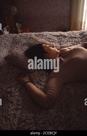 Giovane donna sdraiata sul letto Foto Stock