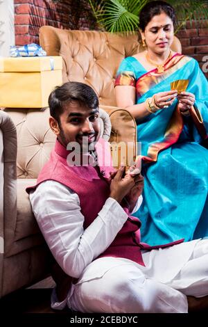 Happy Indian Family giocare teen patti o tre carte gioco la notte del festival di diwali in abiti tradizionali a casa Foto Stock