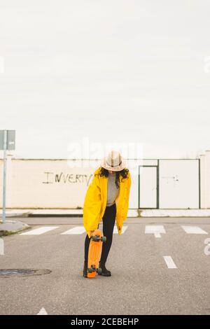 Giovane donna slim in padella gialla in skateboard in strada Foto Stock