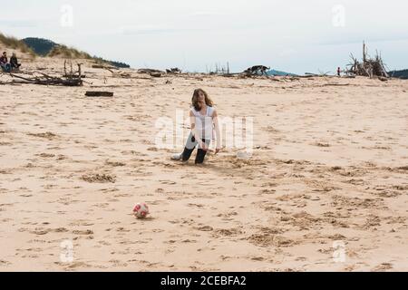 Teenager che gioca con la palla sulla spiaggia Foto Stock