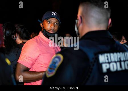 Washington, DC, USA, 27 agosto 2020. Nella foto: Un protestore di fronte a una linea di ufficiali di polizia Metropolitan (DC) fa eccezione al suo trattamento da parte di Foto Stock