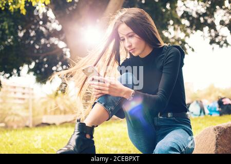 Giovane donna che usa lo smartphone nel parco Foto Stock