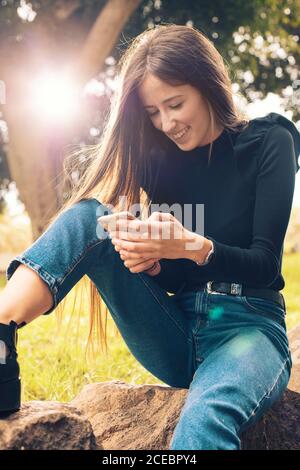 Giovane donna che usa lo smartphone nel parco Foto Stock
