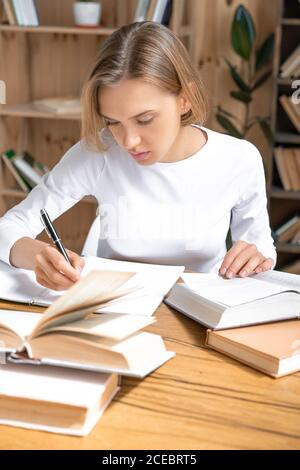 Giovane studentessa concentrata che fa i compiti e si prepara agli esami Foto Stock