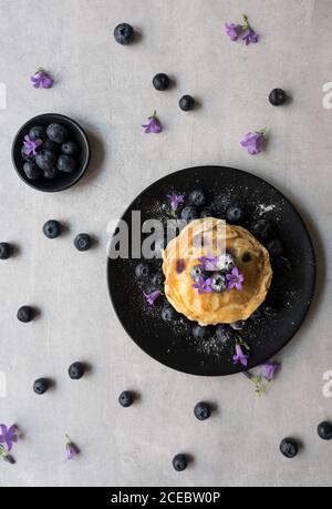 Stack di gustose briciole appetitose con fiori di mirtillo e viola decorazione su un tavolo Foto Stock