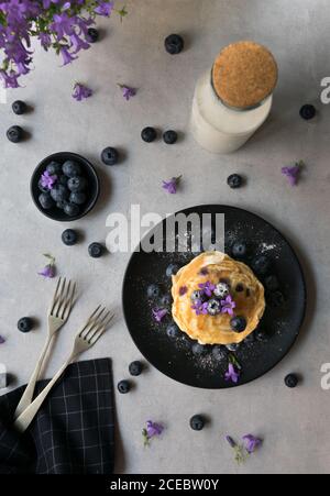 Stack di gustose briciole appetitose con fiori di mirtillo e viola decorazione su un tavolo Foto Stock