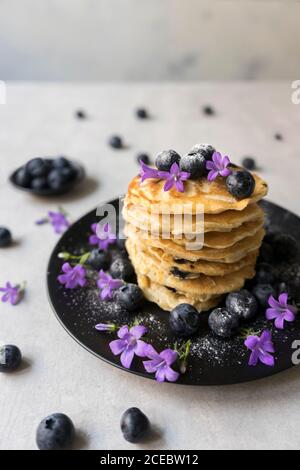 Stack di gustose briciole appetitose con fiori di mirtillo e viola decorazione su un tavolo Foto Stock