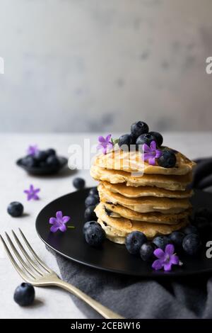 Stack di gustose briciole appetitose con fiori di mirtillo e viola decorazione su un tavolo Foto Stock