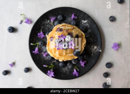 Stack di gustose briciole appetitose con fiori di mirtillo e viola decorazione su un tavolo Foto Stock