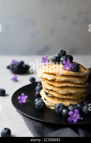 Stack di gustose briciole appetitose con fiori di mirtillo e viola decorazione su un tavolo Foto Stock