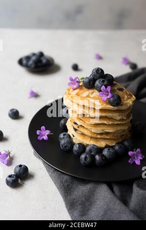 Stack di gustose briciole appetitose con fiori di mirtillo e viola decorazione su un tavolo Foto Stock