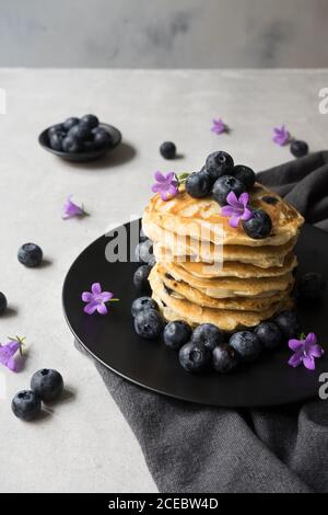 Stack di gustose briciole appetitose con fiori di mirtillo e viola decorazione su un tavolo Foto Stock