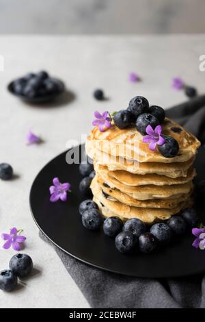 Stack di gustose briciole appetitose con fiori di mirtillo e viola decorazione su un tavolo Foto Stock