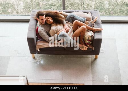 Giovane coppia multirazziale abbracciata sul divano Foto Stock