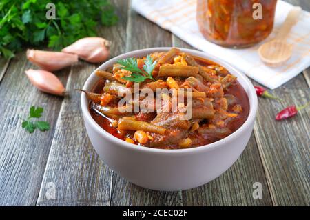 Lobio di pomodoro di baccelli di fagioli verdi in una ciotola su sfondo di legno. Piatto quaresimale. Foto Stock