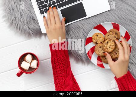 Le mani delle donne che scrivano sulla tastiera con cacao e biscotti Foto Stock