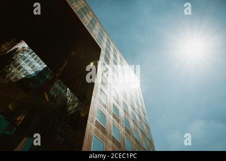 Da sotto un sole luminoso che splende sul cielo blu sulla facciata di un edificio moderno sulla strada di Londra, Inghilterra Foto Stock