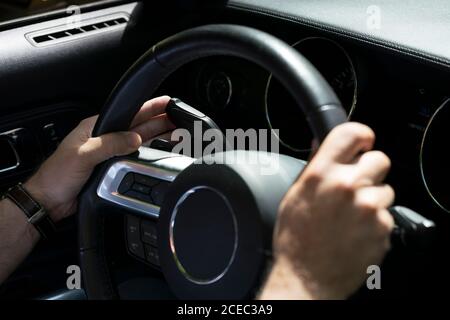 Colpo di raccolto di uomo che guida un'auto moderna che tiene il volante e premendo la leva dell'indicatore luminoso Foto Stock