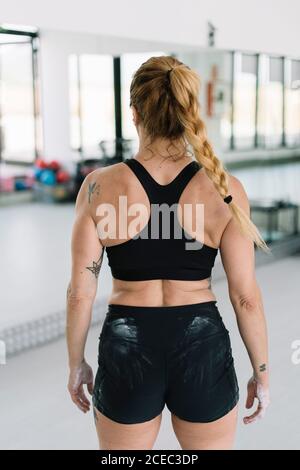vista posteriore di atleta femminile anonima con le mani coperte gesso in piedi in palestra durante l'allenamento Foto Stock