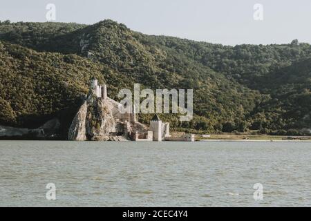 La vista della fortezza di Golubac sulle rive del Fiume Danubio in Serbia, al confine tra Romania e Serbia con foreste colline sullo sfondo Foto Stock