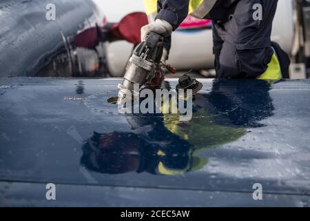 Coltivare l'uomo in uniforme alimentando l'aereo moderno mentre si lavora campo aereo Foto Stock